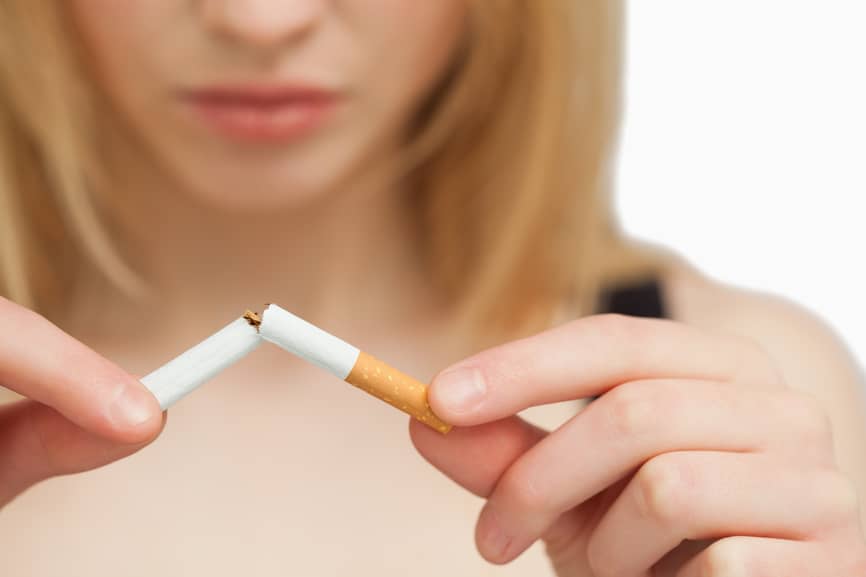 Serious woman breaking a cigarette against white background