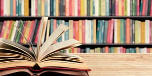 book open and pages fluttering - entire bookcase of books behind it