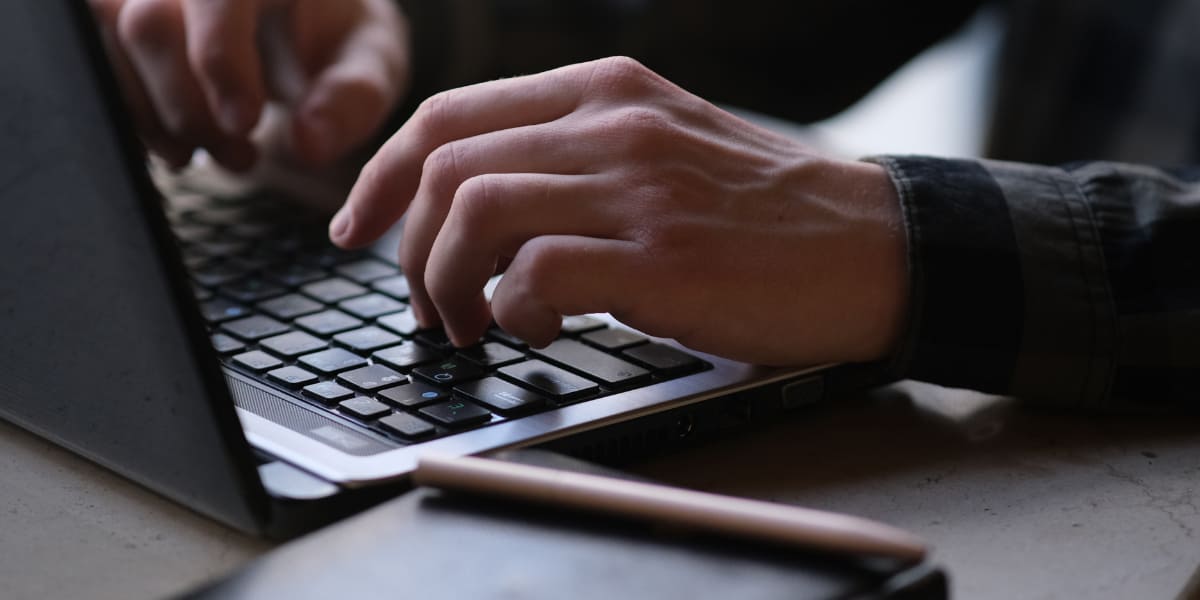 fingers rest on a laptops keyboard