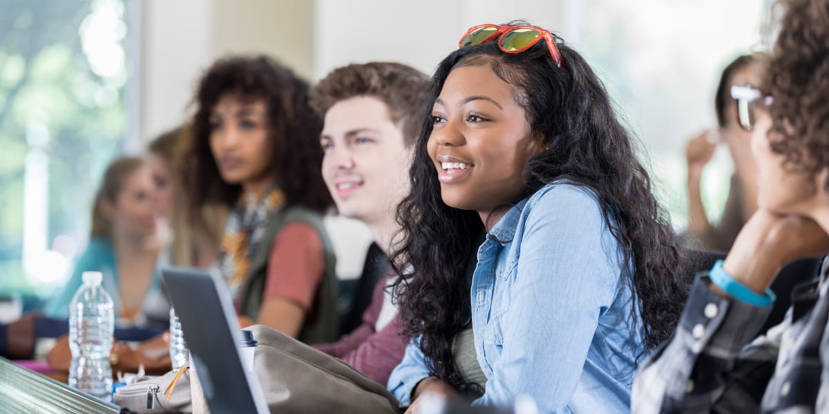 college students engage in a class and smile