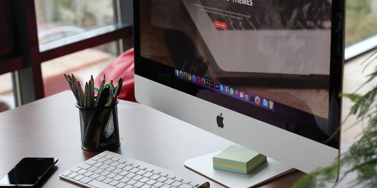 computer monitor with a pencil cup and phone sitting on the desk with it