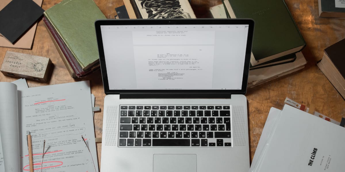 laptop with pages surrounding it containing highlighted words
