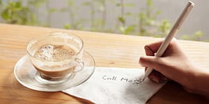 Coffee cup on a desk with a folded napkin with someone writing on it