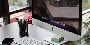 computer monitor with a pencil cup and phone sitting on the desk with it