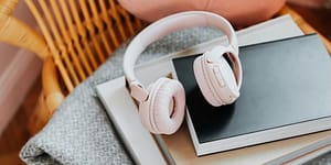 pink headphones sit atop notebooks and a grey blanket