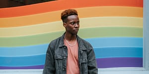person stands in front of a rainbow wall