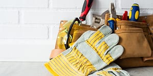 tool belt containing tools and yellow work gloves
