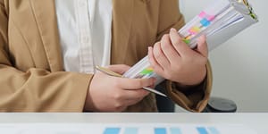 woman holds a binder with colorful tabs marking her place