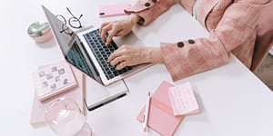 woman wearing a pink blazer using a laptop