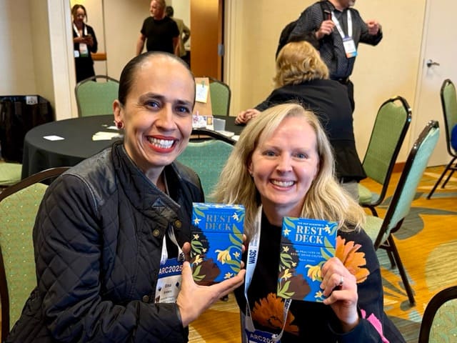 Two woman hold up boxes of cards: The Nap Ministry's Rest Deck
