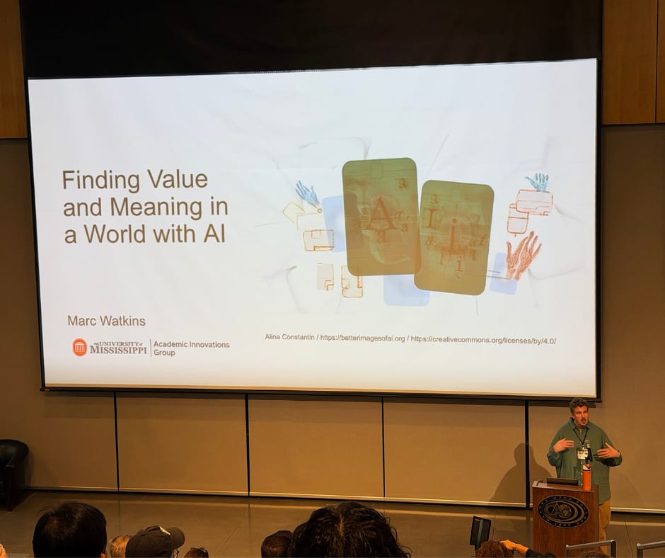 Man presents at the front of a large lecture hall with a slide that reads: Finding Value and Meaning in a World of AI