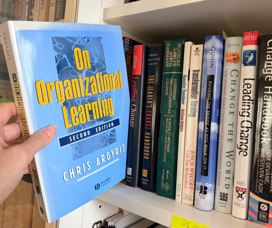 Bookshelf with a book being held out from the rest. Chris Argyris' On Organizational Learning