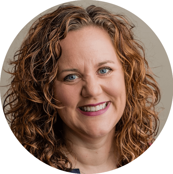 Woman with red, curly hair smiles at the camera