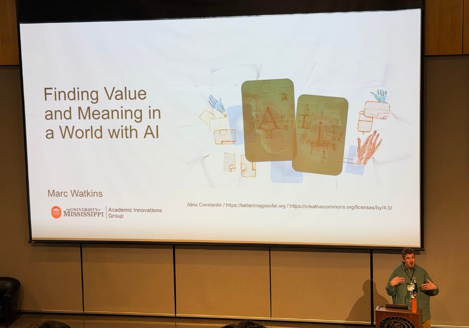 Man presents at the front of a large lecture hall with a slide that reads: Finding Value and Meaning in a World of AI