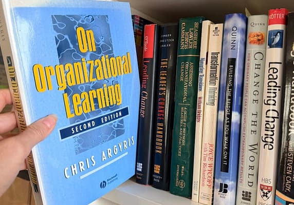 Bookshelf with a book being held out from the rest. Chris Argyris' On Organizational Learning